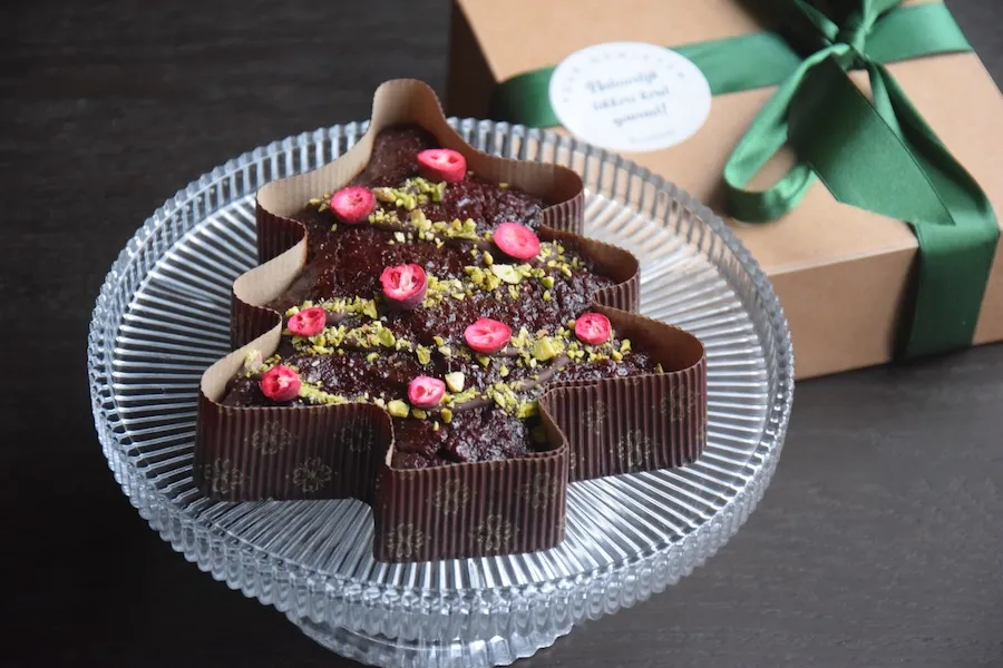 Gezonde chocoladetaart in de vorm van een kerstboom met pure chocolade, pistachenoten en gevriesdroogde cranberry